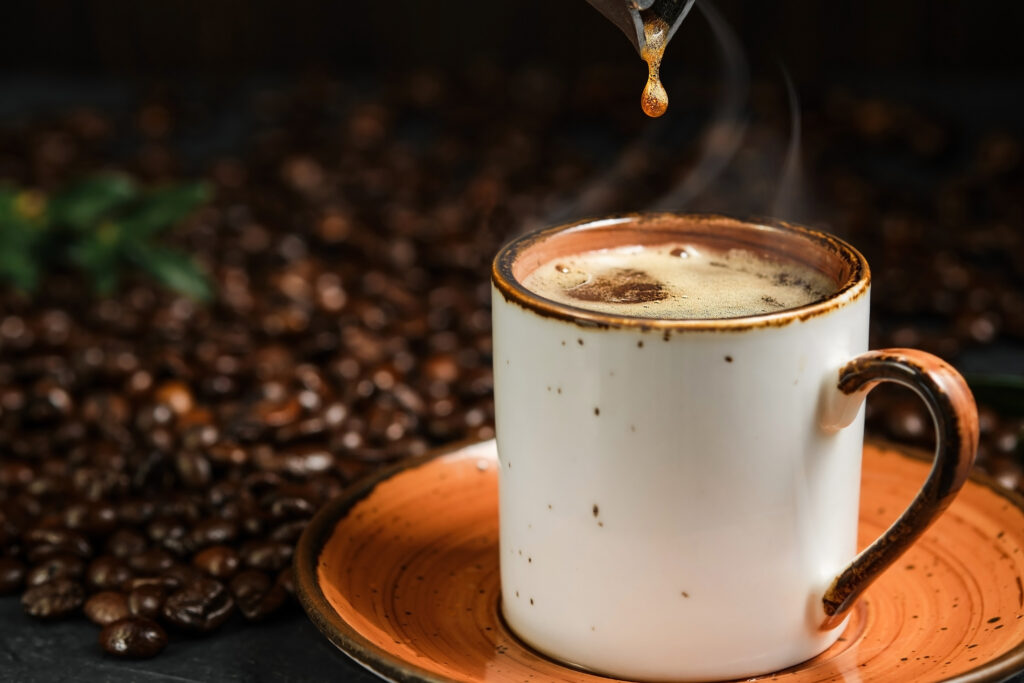 Taza humeante de café de especialidad con granos de café al lado